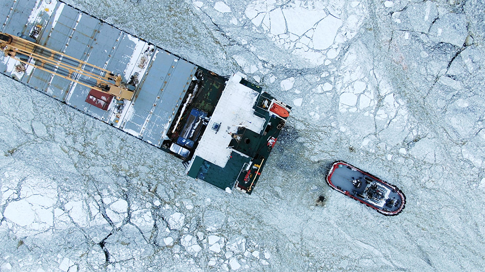 Aerial view of tug and ship sailing through ice