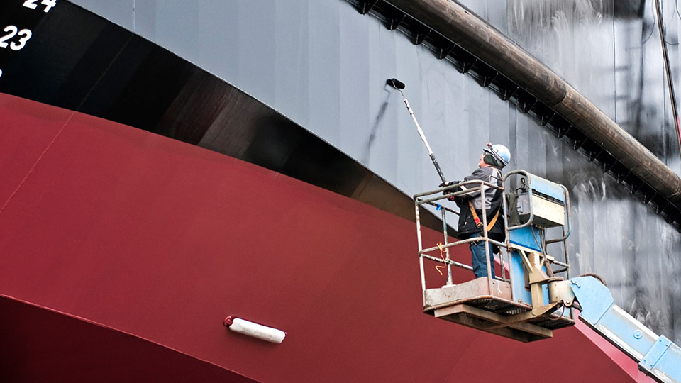 Worker painting a ship hull